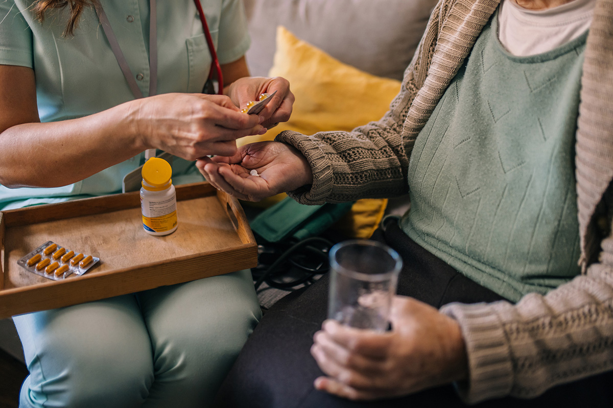 Medication Administration A Nurse Visits An Elderly Woman And Gives Her Medicine