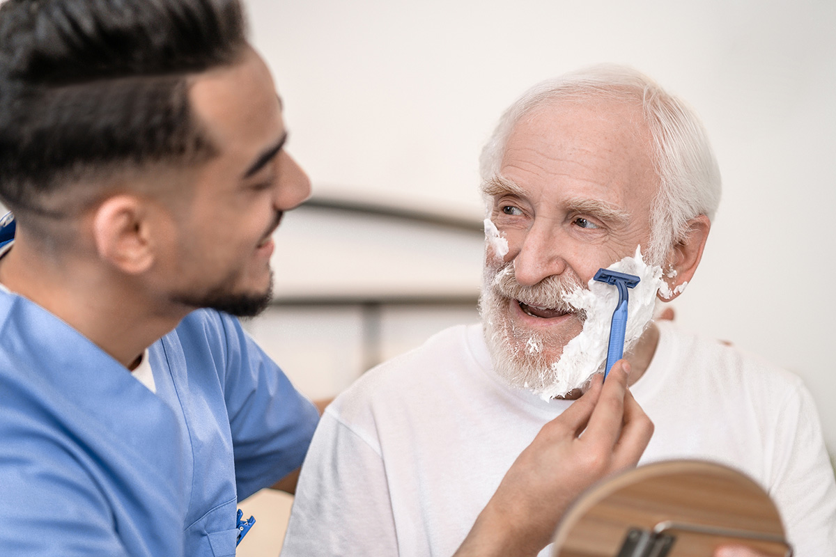 Personal Care Caring Volunteer Giving An Elderly Gentleman A Shave